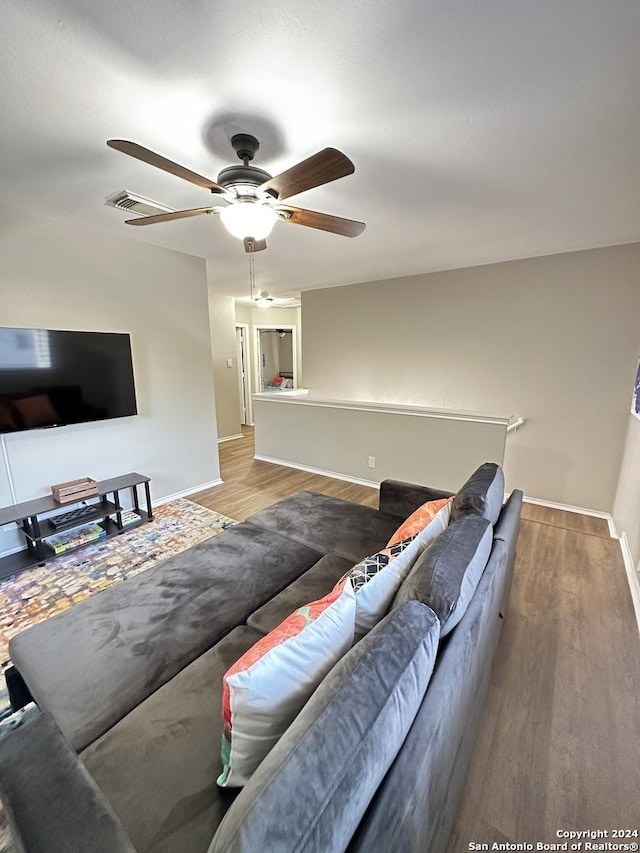 living room with wood finished floors, a ceiling fan, and baseboards