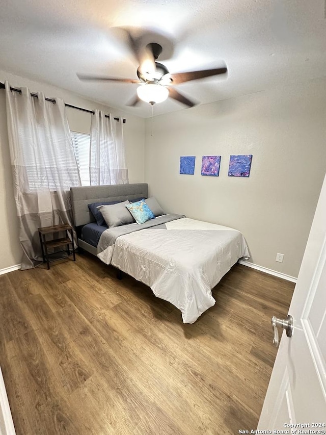 bedroom featuring ceiling fan, wood finished floors, and baseboards