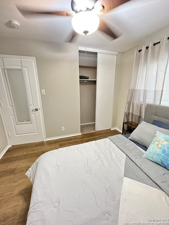 bedroom featuring ceiling fan, a closet, baseboards, and wood finished floors