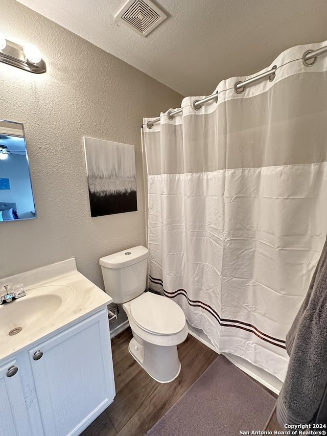 full bath featuring visible vents, a textured wall, toilet, wood finished floors, and a textured ceiling