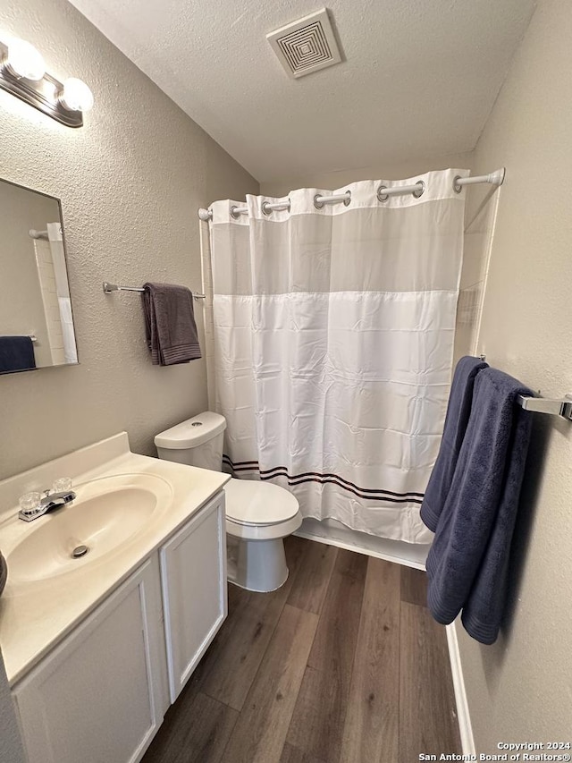 bathroom featuring visible vents, a textured wall, a textured ceiling, and wood finished floors