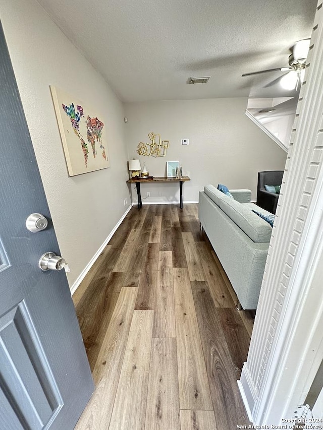 interior space featuring baseboards, visible vents, ceiling fan, wood finished floors, and a textured ceiling