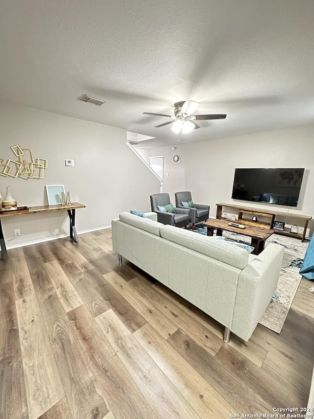 living room featuring visible vents, ceiling fan, a textured ceiling, wood finished floors, and baseboards