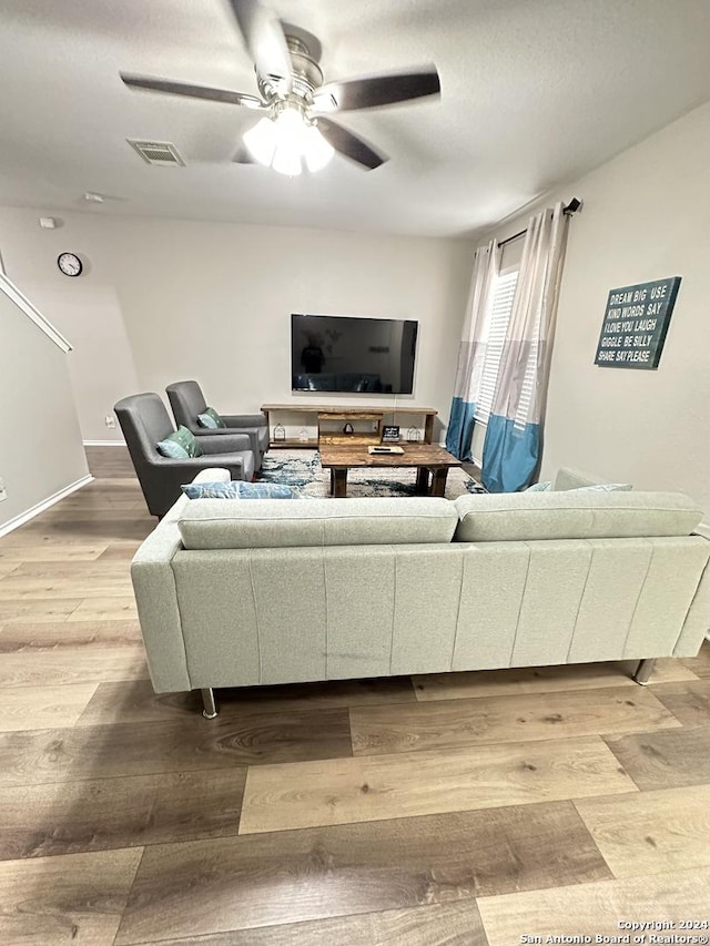 living room with baseboards, ceiling fan, visible vents, and wood finished floors