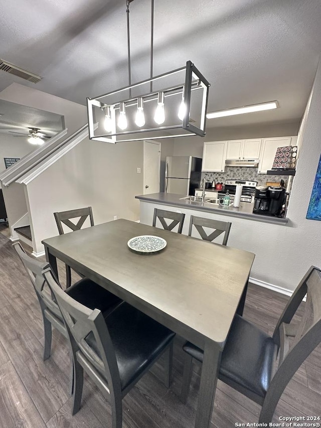 dining room featuring ceiling fan, stairs, visible vents, and wood finished floors