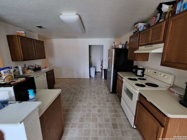 kitchen featuring a textured ceiling, white appliances, and light tile patterned floors