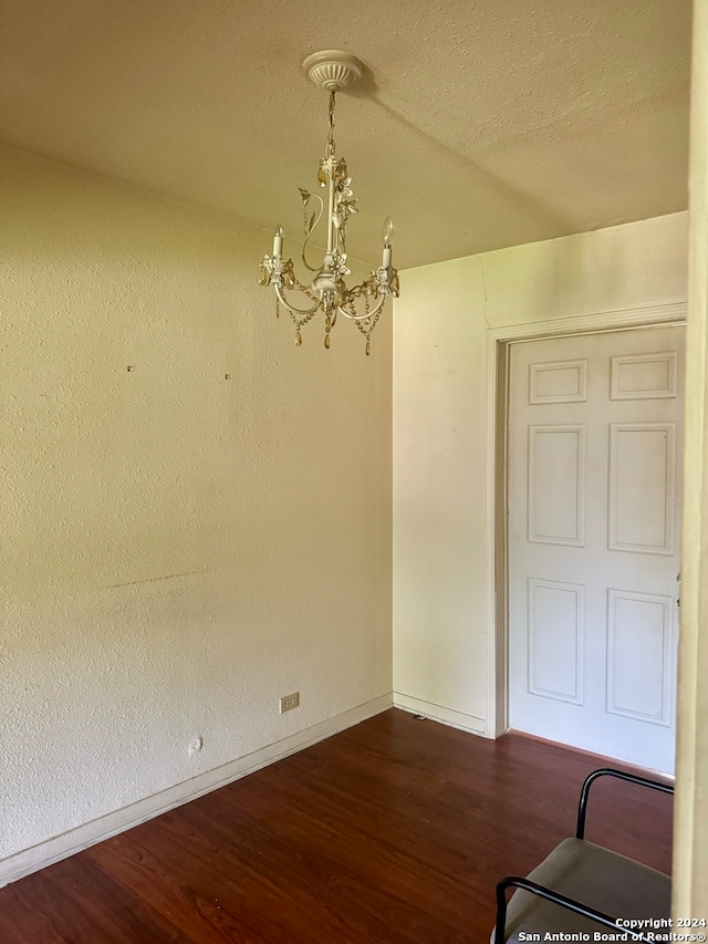 spare room featuring a textured ceiling, a notable chandelier, and wood-type flooring