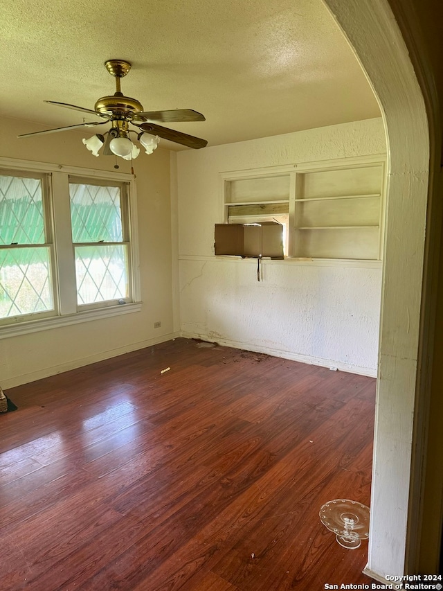 empty room with hardwood / wood-style floors, ceiling fan, a textured ceiling, and built in shelves