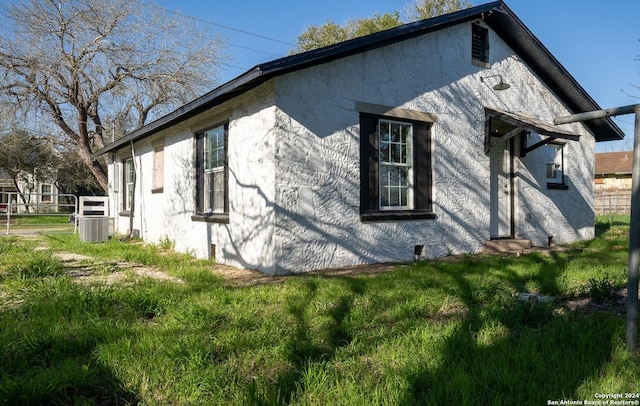 view of side of home with a lawn and central AC