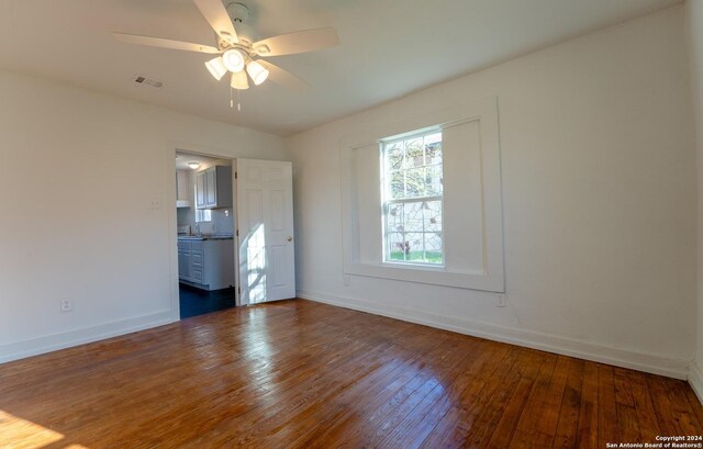 unfurnished bedroom featuring ceiling fan, ensuite bath, sink, and dark wood-type flooring