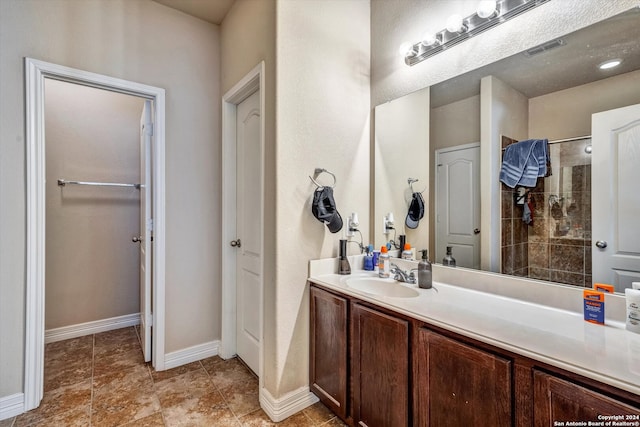 bathroom featuring tile patterned flooring, a tile shower, and vanity