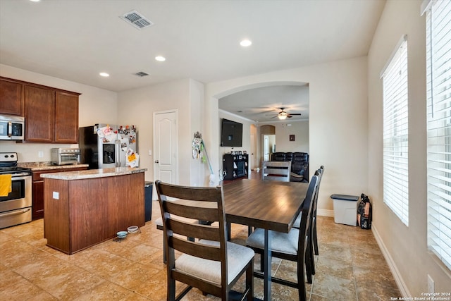 kitchen with stainless steel appliances, plenty of natural light, light tile patterned floors, a center island, and ceiling fan