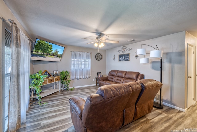 living room featuring a textured ceiling, light hardwood / wood-style flooring, and ceiling fan