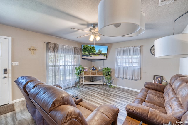 living room featuring a textured ceiling, light hardwood / wood-style flooring, and ceiling fan