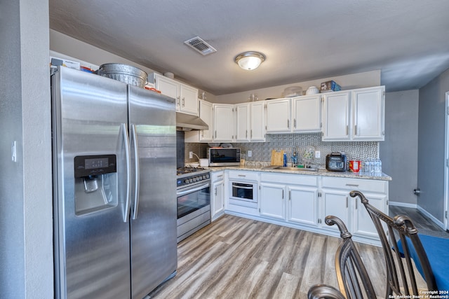 kitchen with appliances with stainless steel finishes, decorative backsplash, sink, and white cabinetry