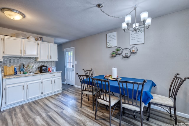 kitchen featuring tasteful backsplash, hanging light fixtures, white cabinetry, light hardwood / wood-style floors, and an inviting chandelier