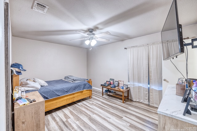 bedroom with ceiling fan, hardwood / wood-style flooring, and a textured ceiling