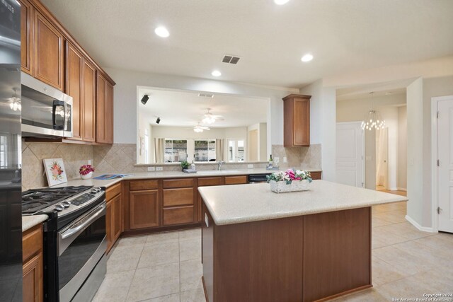 kitchen featuring ceiling fan, backsplash, appliances with stainless steel finishes, light tile patterned floors, and kitchen peninsula