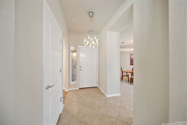 corridor featuring light tile patterned floors and a notable chandelier