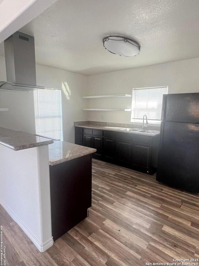 kitchen with dark wood-type flooring, freestanding refrigerator, range hood, a textured ceiling, and dark cabinetry