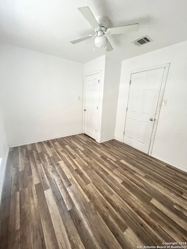 interior space featuring ceiling fan, dark wood-type flooring, visible vents, and baseboards