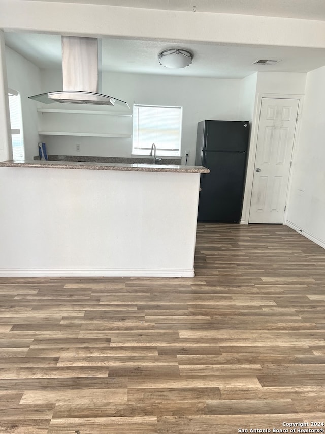 kitchen with dark hardwood / wood-style flooring, island range hood, black refrigerator, and sink