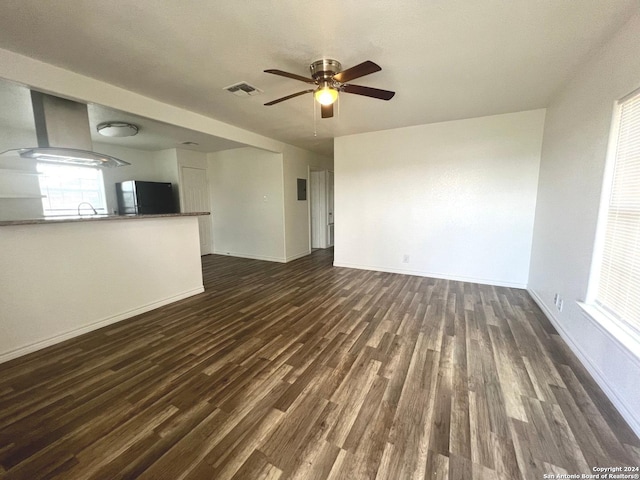 unfurnished living room with baseboards, visible vents, a ceiling fan, dark wood-style floors, and a sink