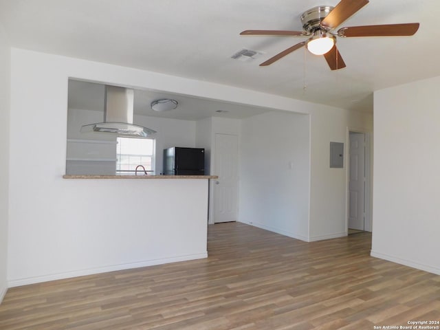 unfurnished living room with light wood finished floors, visible vents, a sink, electric panel, and baseboards