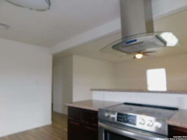 kitchen featuring island range hood, wood finished floors, light countertops, dark brown cabinets, and stainless steel electric stove