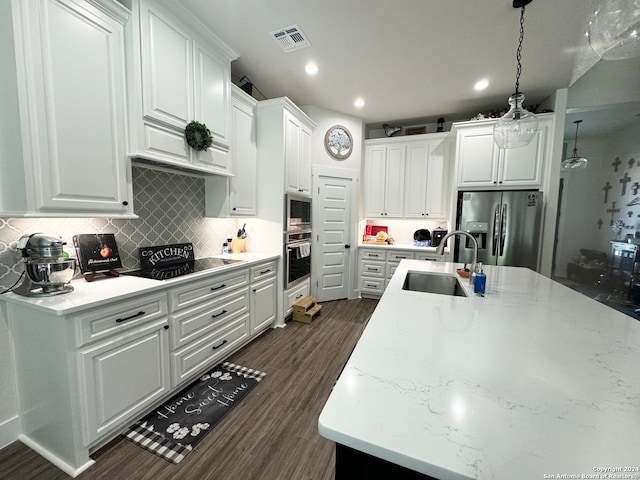 kitchen with white cabinets, hanging light fixtures, stainless steel appliances, sink, and dark wood-type flooring