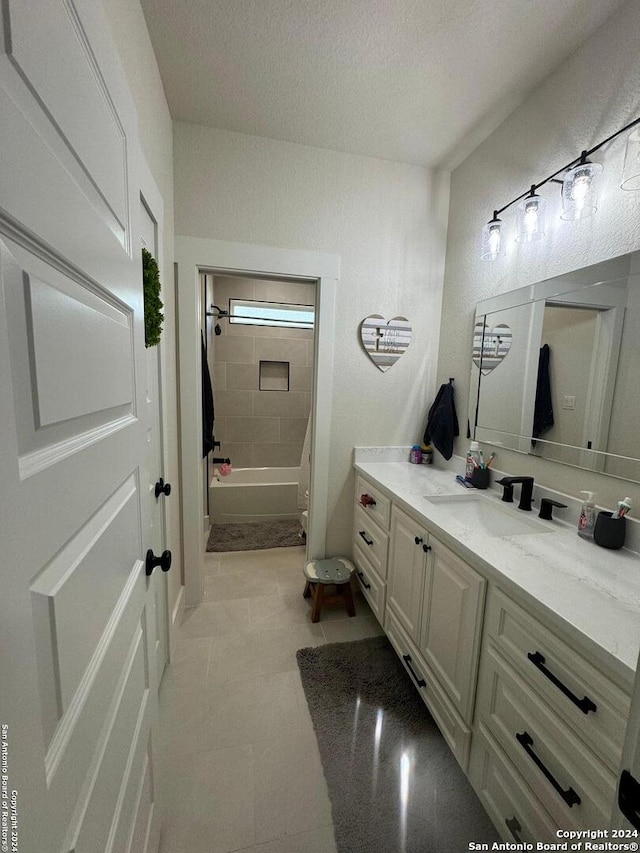 bathroom featuring a textured ceiling, vanity, and tiled shower / bath combo