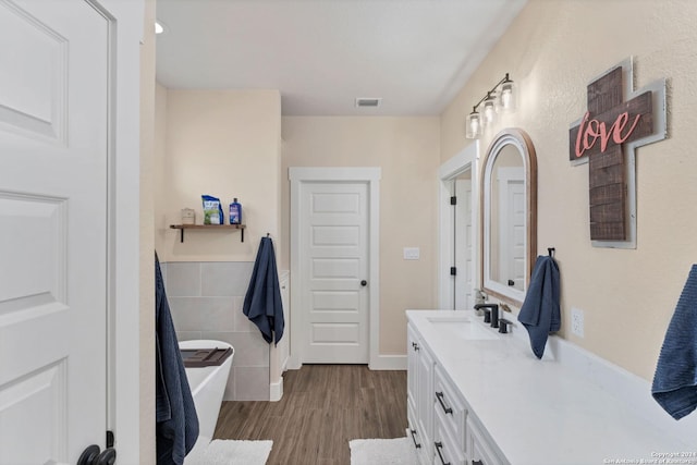 bathroom with hardwood / wood-style flooring, vanity, tile walls, and a bathtub