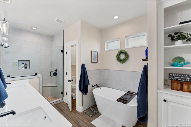 full bathroom featuring toilet, tile walls, vanity, independent shower and bath, and hardwood / wood-style floors