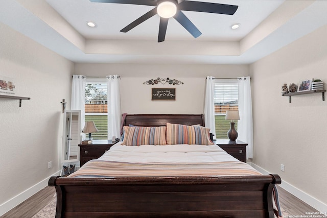 bedroom featuring a tray ceiling, light hardwood / wood-style flooring, and ceiling fan