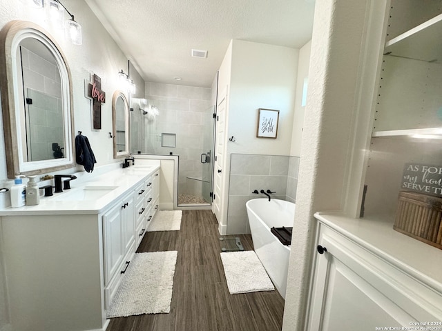 bathroom featuring hardwood / wood-style floors, vanity, a textured ceiling, independent shower and bath, and tile walls