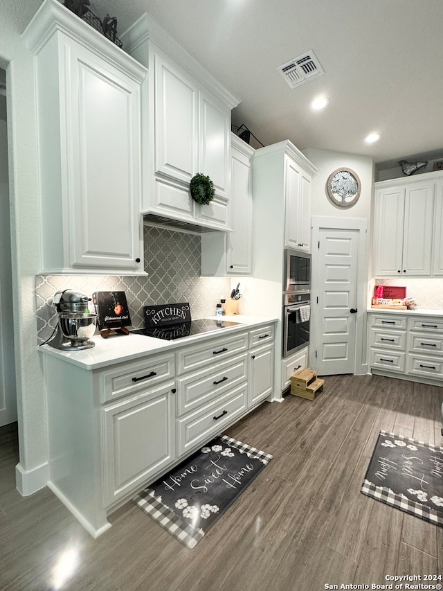 kitchen featuring tasteful backsplash, hardwood / wood-style flooring, stainless steel appliances, and white cabinets