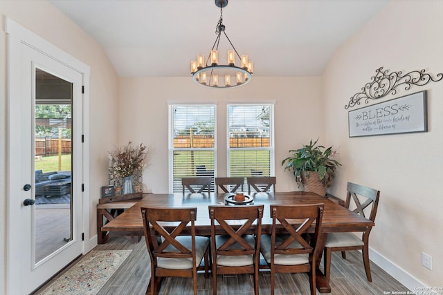 dining space with hardwood / wood-style flooring, lofted ceiling, and a chandelier