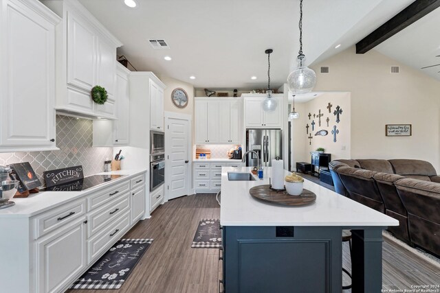 kitchen featuring pendant lighting, sink, appliances with stainless steel finishes, white cabinetry, and an island with sink