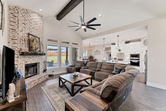 living room with beam ceiling, high vaulted ceiling, dark hardwood / wood-style floors, a fireplace, and ceiling fan with notable chandelier