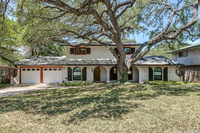 mediterranean / spanish home with a garage, brick siding, driveway, and a front lawn