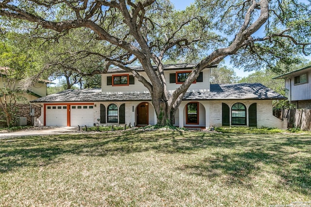 mediterranean / spanish home with brick siding, a garage, cooling unit, driveway, and a front lawn