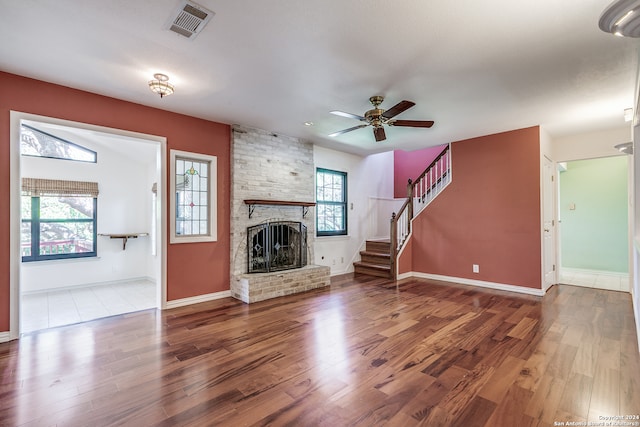 unfurnished living room with a brick fireplace, hardwood / wood-style floors, and a healthy amount of sunlight