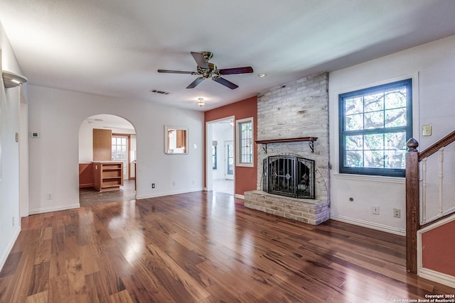 unfurnished living room featuring ceiling fan, a fireplace, dark wood finished floors, and visible vents