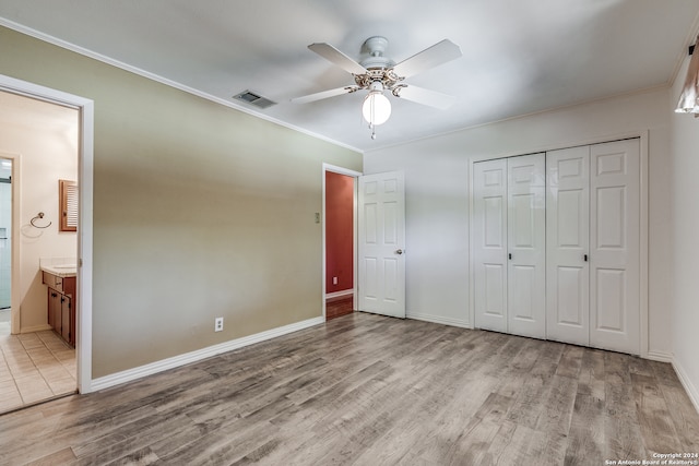 unfurnished bedroom with hardwood / wood-style floors, crown molding, a closet, ceiling fan, and connected bathroom