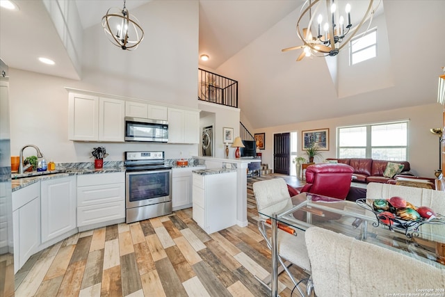 kitchen with stainless steel appliances, light hardwood / wood-style floors, white cabinetry, sink, and high vaulted ceiling