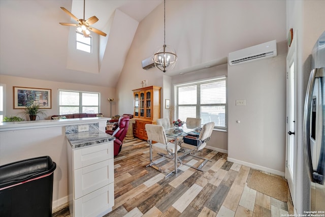 kitchen featuring high vaulted ceiling, a wall mounted AC, ceiling fan with notable chandelier, white cabinetry, and hanging light fixtures