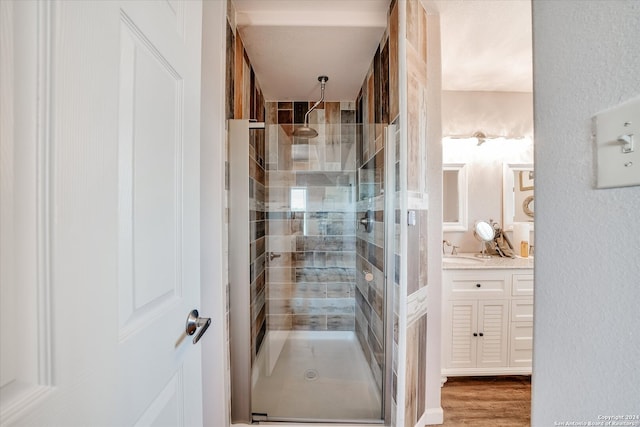 bathroom with hardwood / wood-style floors, a shower with shower door, and vanity