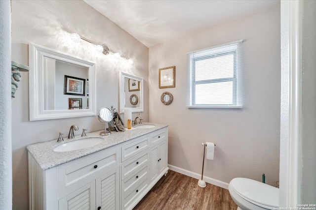 bathroom with toilet, dual vanity, and hardwood / wood-style flooring