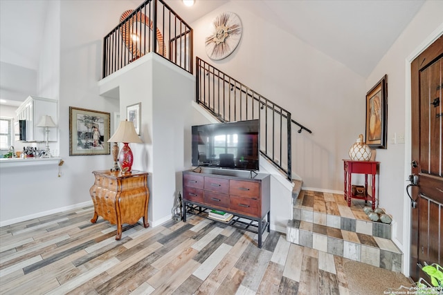 living room with high vaulted ceiling and light wood-type flooring