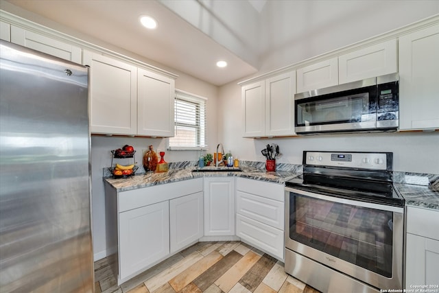 kitchen featuring stainless steel appliances, light hardwood / wood-style floors, sink, stone countertops, and white cabinets